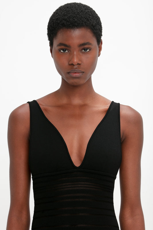 Portrait of a woman with short black hair, wearing a Victoria Beckham Frame Detail Sleeveless Dress In Black with a v-neckline, against a white background.