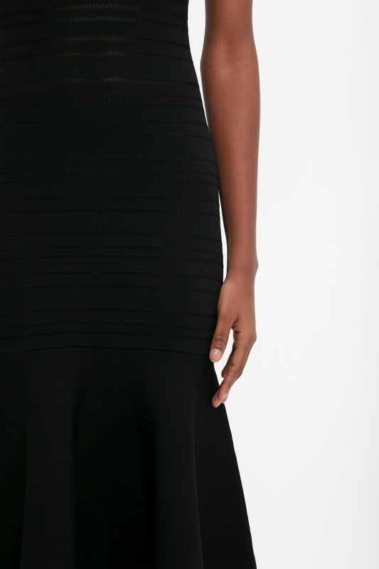 Close-up of a woman in a Victoria Beckham Frame Detail Sleeveless Dress In Black, focusing on her side and arm, with a white background.