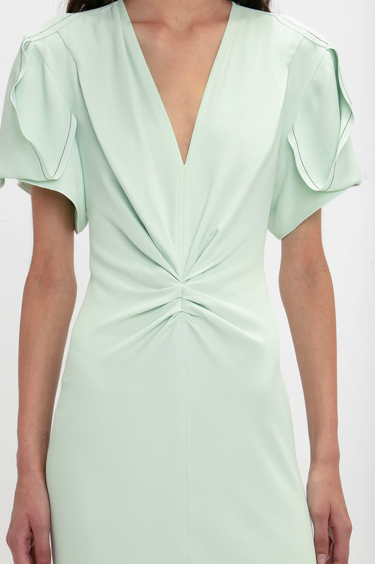 A close up of a woman's body wearing a Victoria Beckham Gathered V-Neck Midi Dress In Jade.