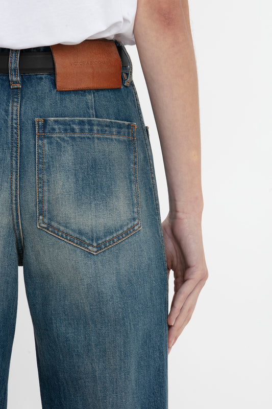 Close-up of a person wearing Victoria Beckham Alina Jean in indigrey wash with a brown leather belt, focusing on the back pocket detail.