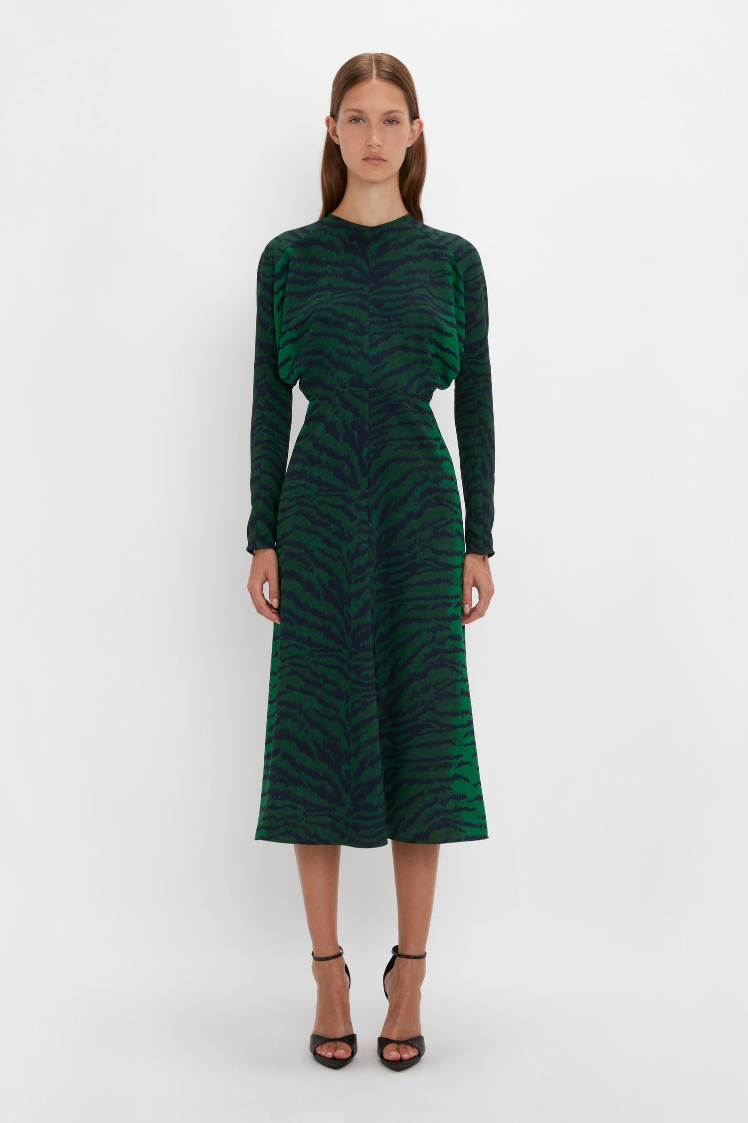 A woman in a Victoria Beckham green-navy tiger print dolman midi dress standing against a white background.