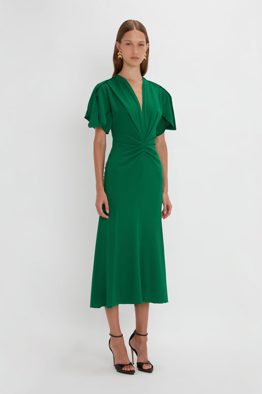 A woman in a Victoria Beckham Gathered V-Neck Midi Dress in Emerald.