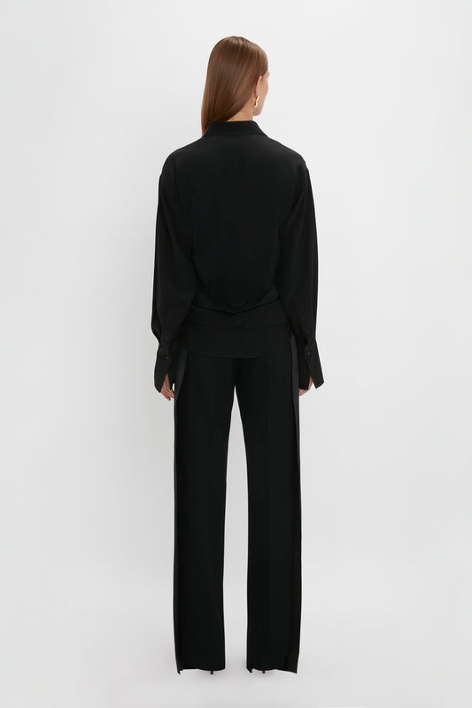 A woman from behind, wearing an oversized Victoria Beckham black blazer and trousers on a white background.