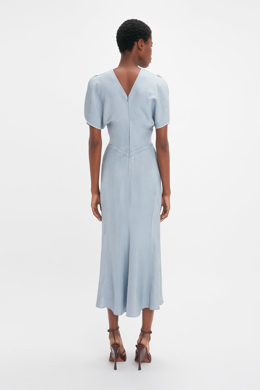 Woman from behind wearing a light blue Exclusive Gathered Waist Midi Dress In Pebble by Victoria Beckham and brown high heels, standing against a white background.