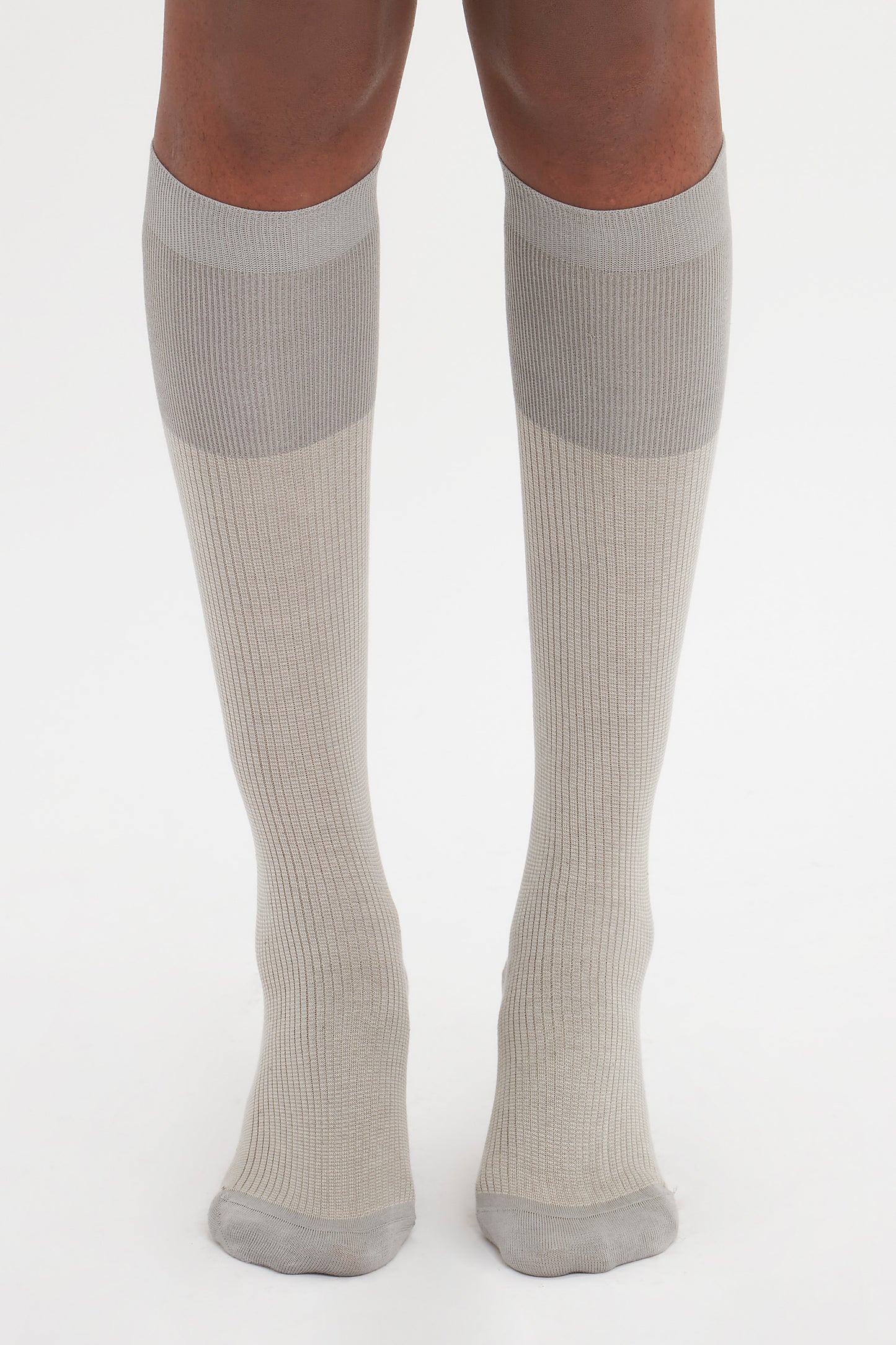The image shows a pair of legs wearing knee-high, light gray Superfine Rib Socks In Lunar Grey by Victoria Beckham made from 100% cotton, standing on a white background—an elevated wardrobe essential for any day.