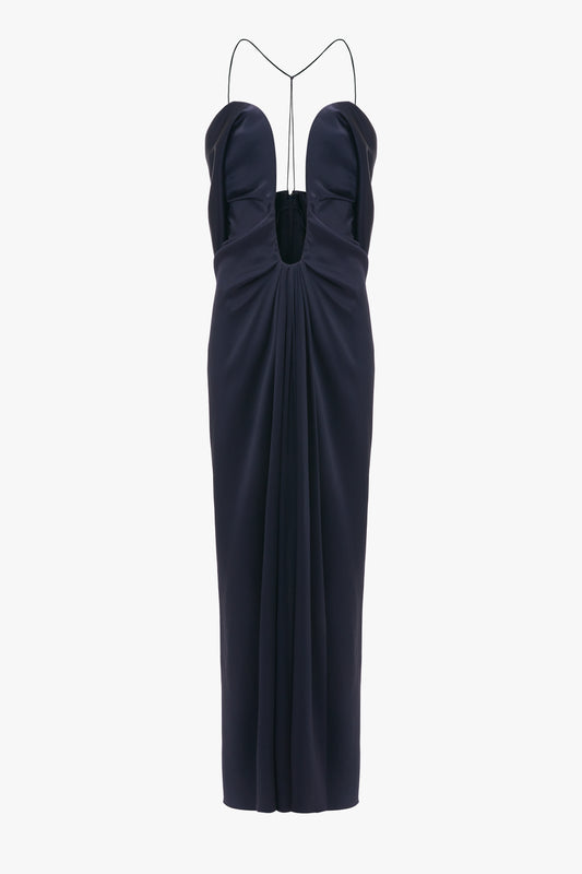 Navy blue evening gown with a plunging neckline and Victoria Beckham Frame Detail Cut-Out Cami Dress In Navy, isolated on a white background.