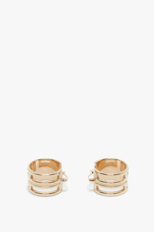 Two Exclusive Frame Hoop Earrings In Gold by Victoria Beckham, with multiple bands, positioned upright against a white background.
