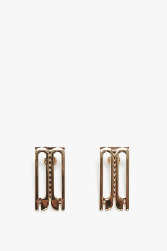 Two Exclusive Frame Stud Earrings In Gold by Victoria Beckham isolated on a white background.