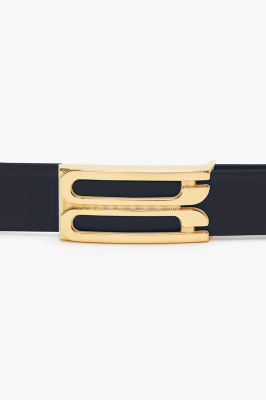 A sleek midnight navy leather belt with polished gold hardware featuring a unique geometric cut-out design, isolated on a white background.