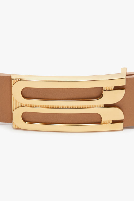 Close-up of a Jumbo Frame Belt In Camel Leather by Victoria Beckham with a golden, textured buckle.