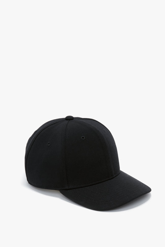 A plain black wool crepe Exclusive Logo Cap In Black positioned to the right on a white background by Victoria Beckham.