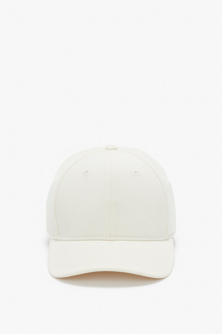 Front view of a plain beige Logo Cap In Antique White by Victoria Beckham against a white background.