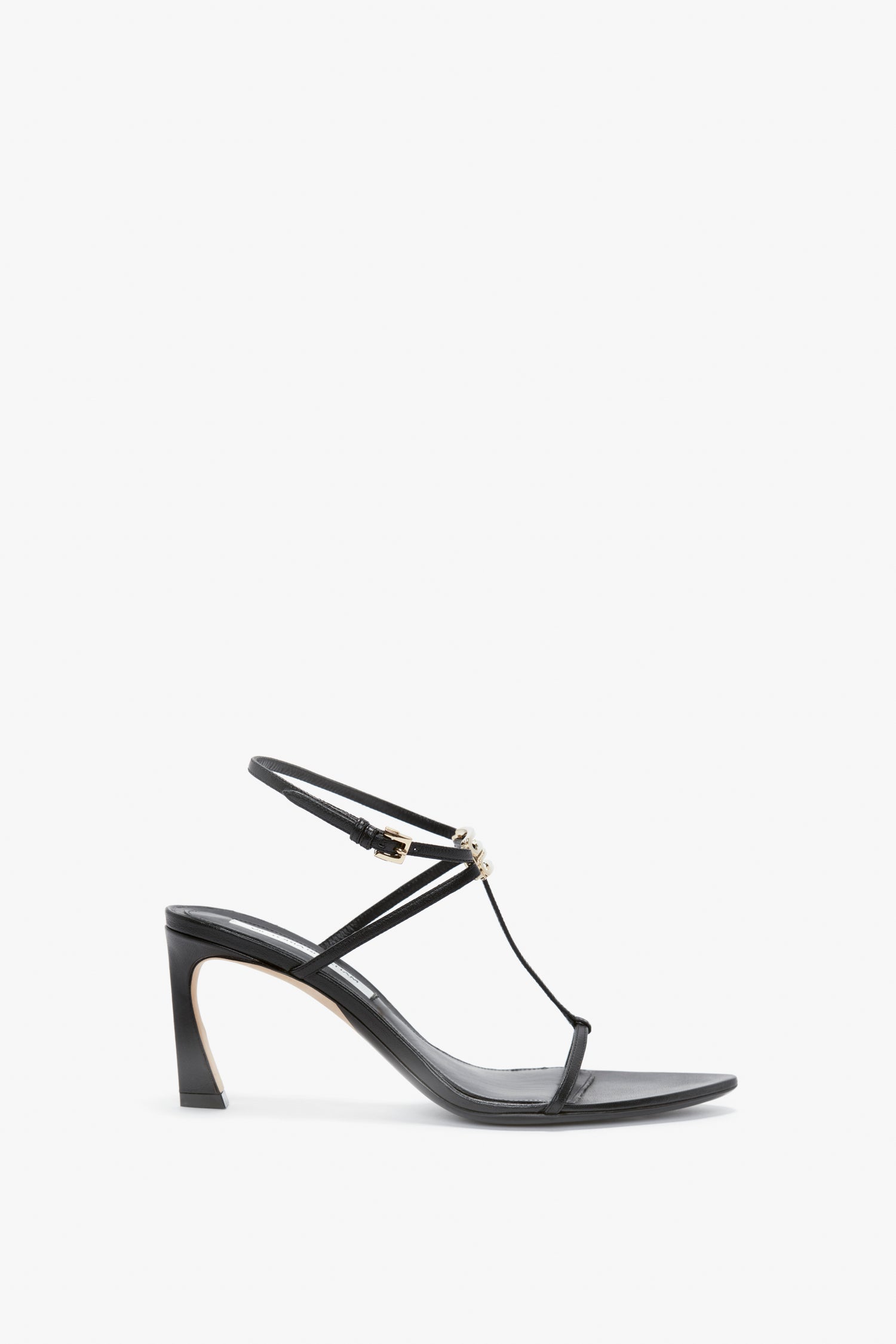 A black high-heeled sandal crafted from supple nappa leather with thin straps, an adjustable ankle strap, and a subtle decorative bead detail on the front. Featuring a moderate V-shaped sculptural heel, the Frame Detail Sandal In Black Leather by Victoria Beckham provides an elegant and sleek appearance.