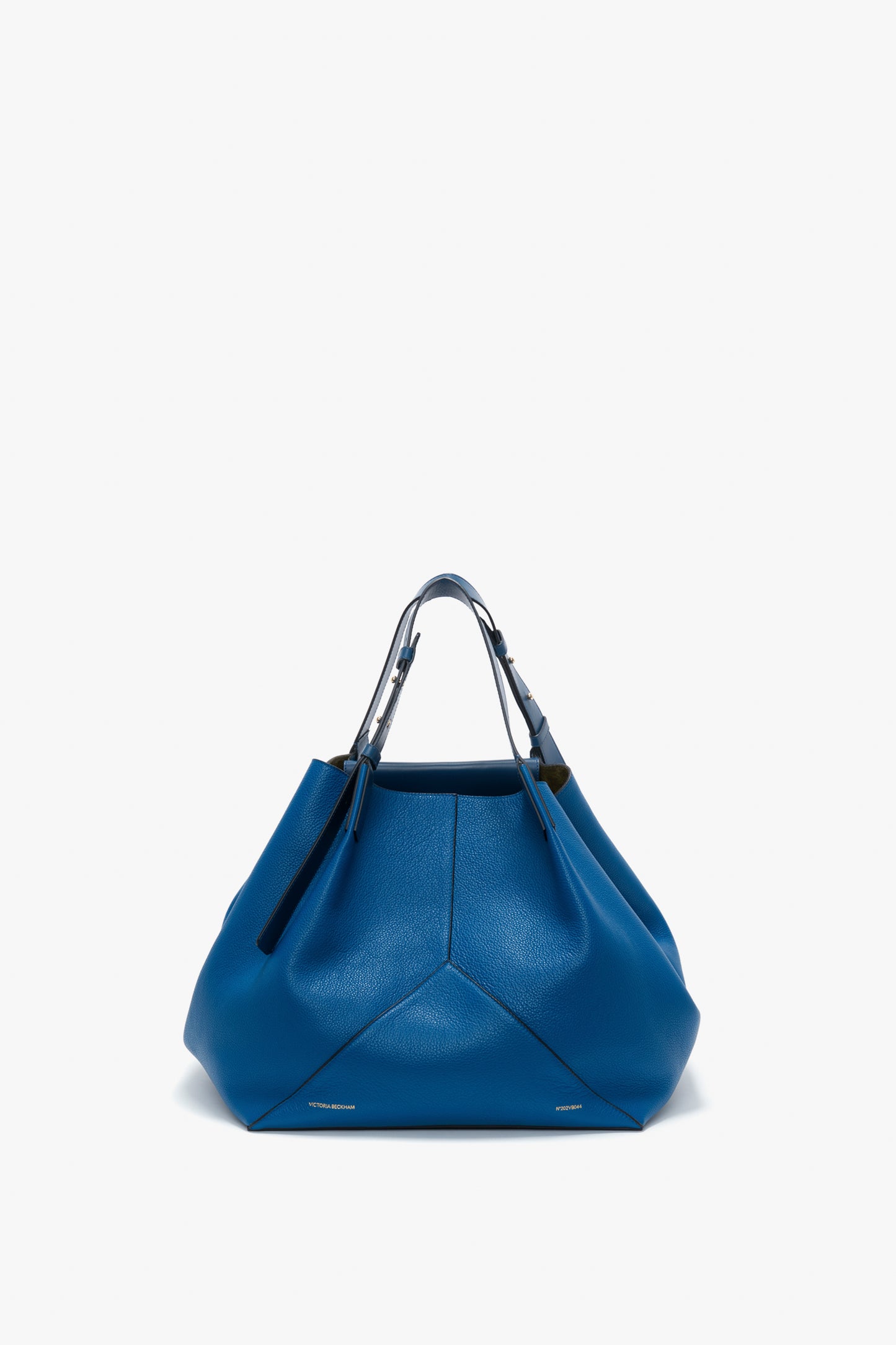 A W11 Medium Tote Bag In Vibrant Blue Leather by Victoria Beckham, made from grained leather with metallic handles, is displayed against a plain white background.