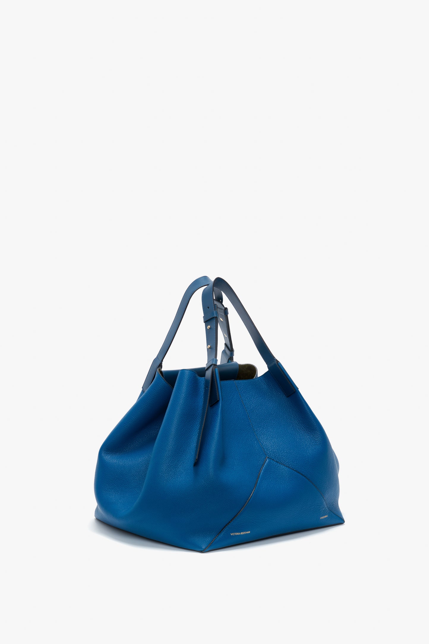 A vibrant blue tote bag with a slouchy design and dual handles, featuring minimal embellishments and a soft, grained leather finish.
Revised Sentence: The Victoria Beckham W11 Medium Tote Bag in Vibrant Blue Leather has a slouchy design and dual handles, featuring minimal embellishments and a soft, grained leather finish.
