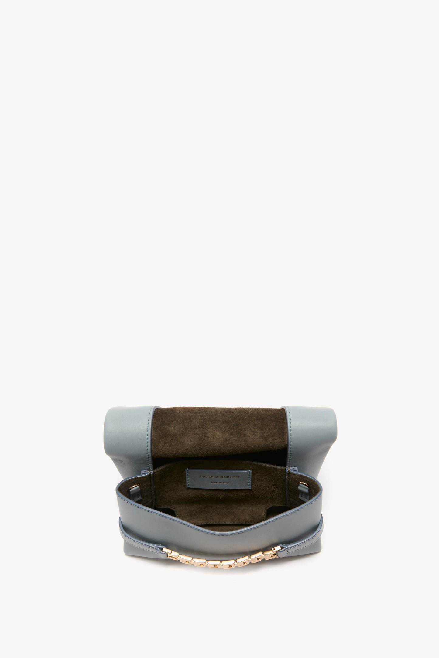 A Mini Chain Pouch Bag With Long Strap In Ice Leather by Victoria Beckham with a gold-tone chain strap is open, revealing the dark interior lining and a label inside.