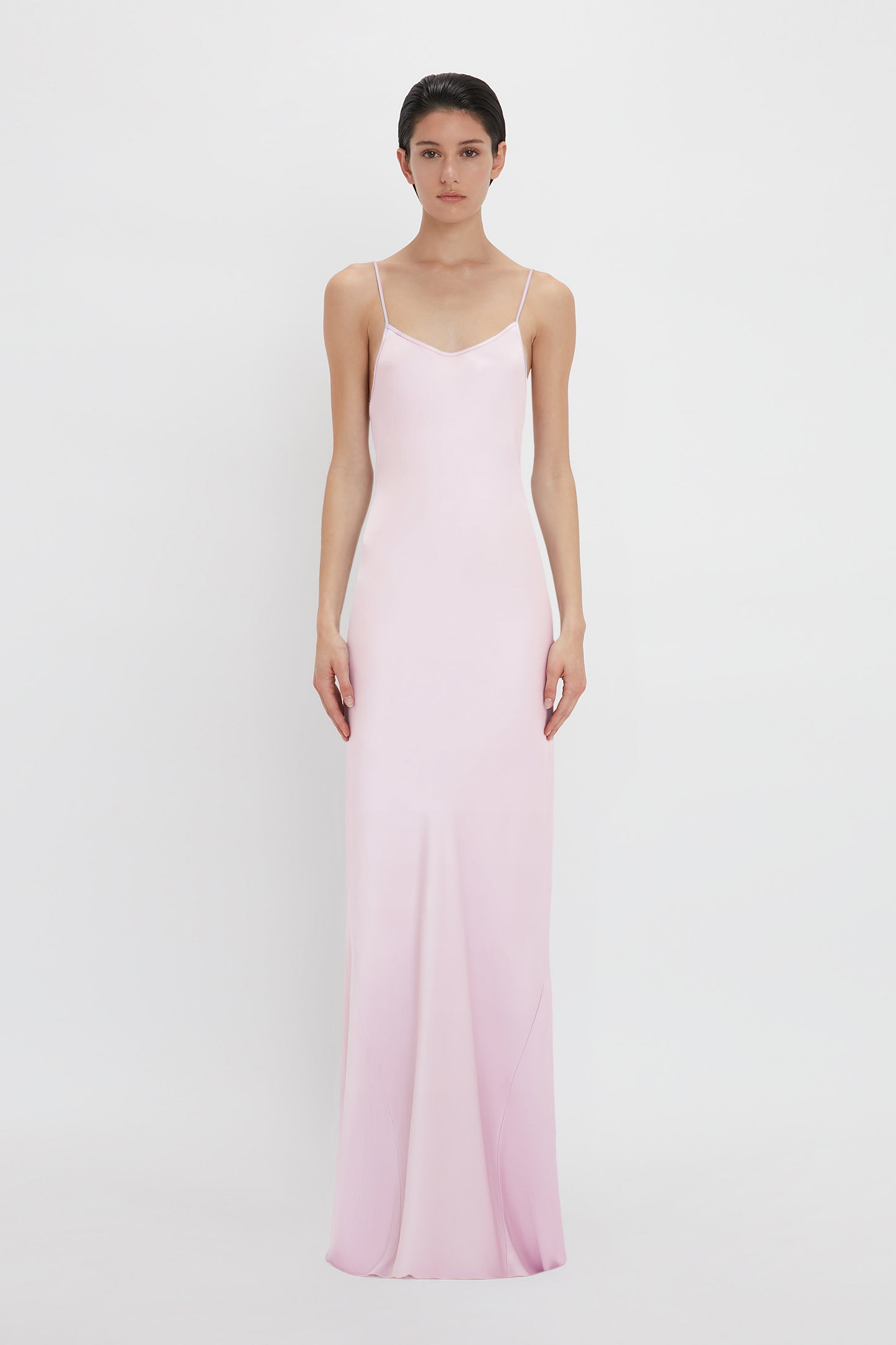 A woman in a Victoria Beckham Low Back Cami Floor-Length Dress In Rosa standing against a white background.
