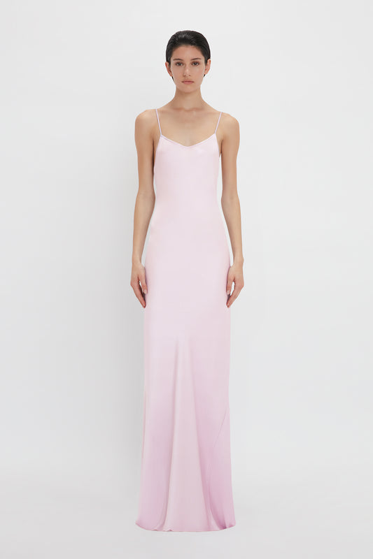 A woman in a Victoria Beckham Low Back Cami Floor-Length Dress In Rosa standing against a white background.