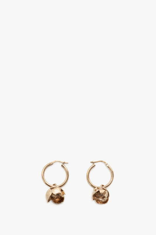 A pair of Exclusive Camellia Flower Hoop Earrings In Gold by Victoria Beckham with small decorative lion heads, isolated on a white background.