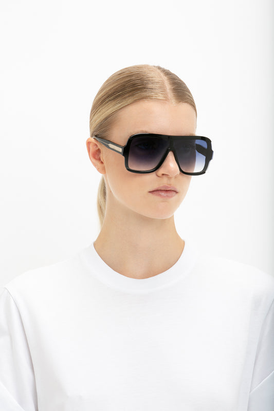 A woman wearing Victoria Beckham's Layered Mask Sunglasses in Black Gradient and a plain white t-shirt against a white background.