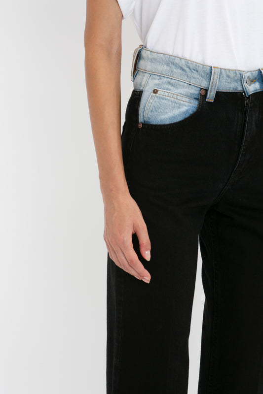 Close-up of a person wearing a white t-shirt and high waist Julia Jean In Contrast Wash jeans by Victoria Beckham with their left hand resting by their side.