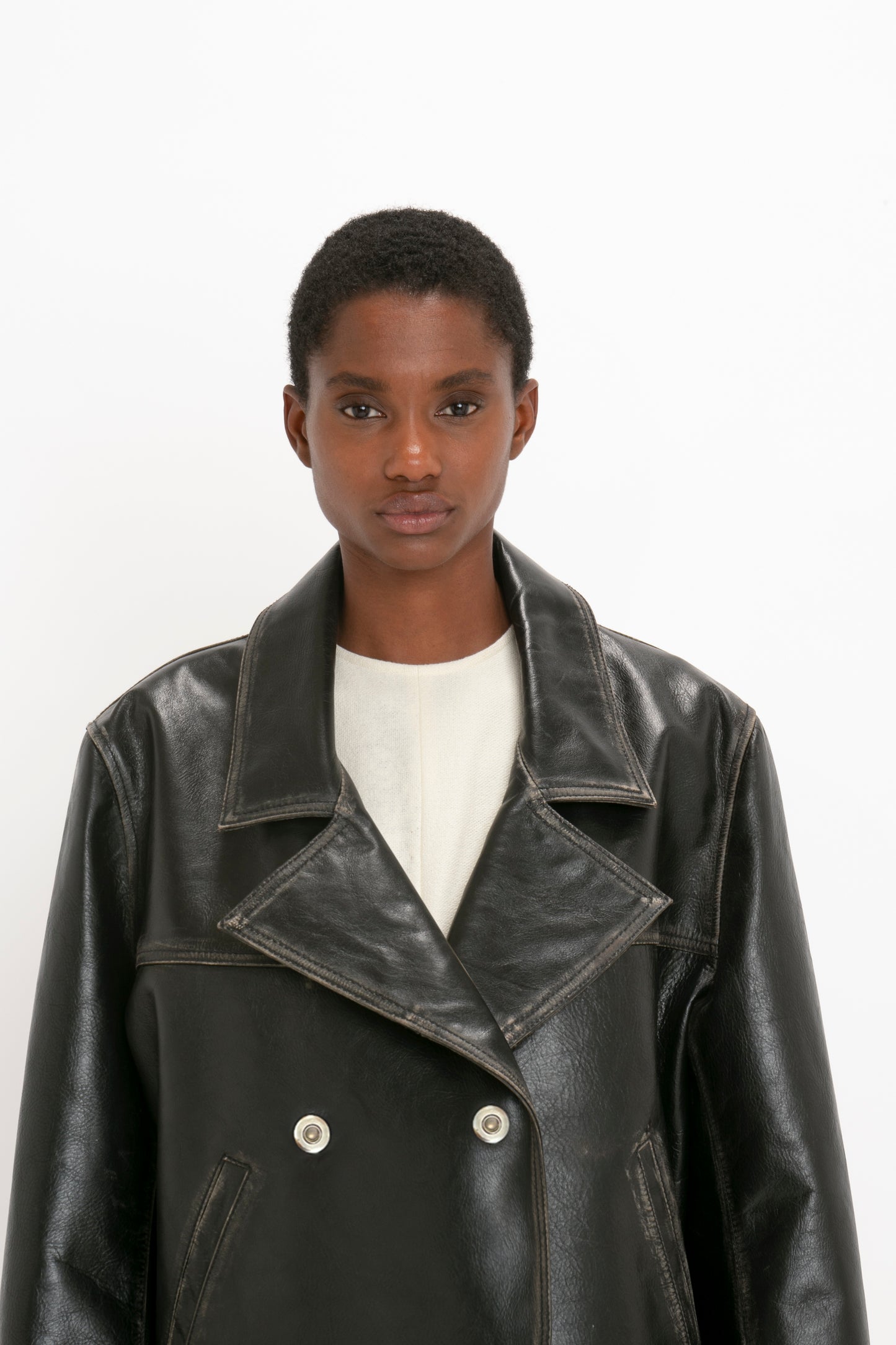 A person with short hair is wearing an **Oversized Leather Jacket In Black** by **Victoria Beckham** over a white top, standing against a plain white background.