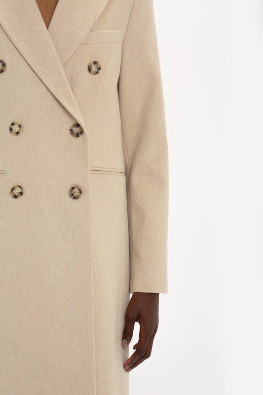 Close-up of a person wearing a Victoria Beckham Tailored Slim Coat in Bone, focusing on the coat's texture and a visible hand.