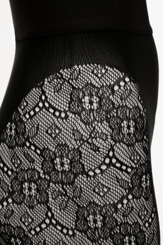 Close-up of Exclusive VB Monogram Lace Tights In Black, featuring intricate floral designs and small dotted details in a seamless construction by Victoria Beckham.