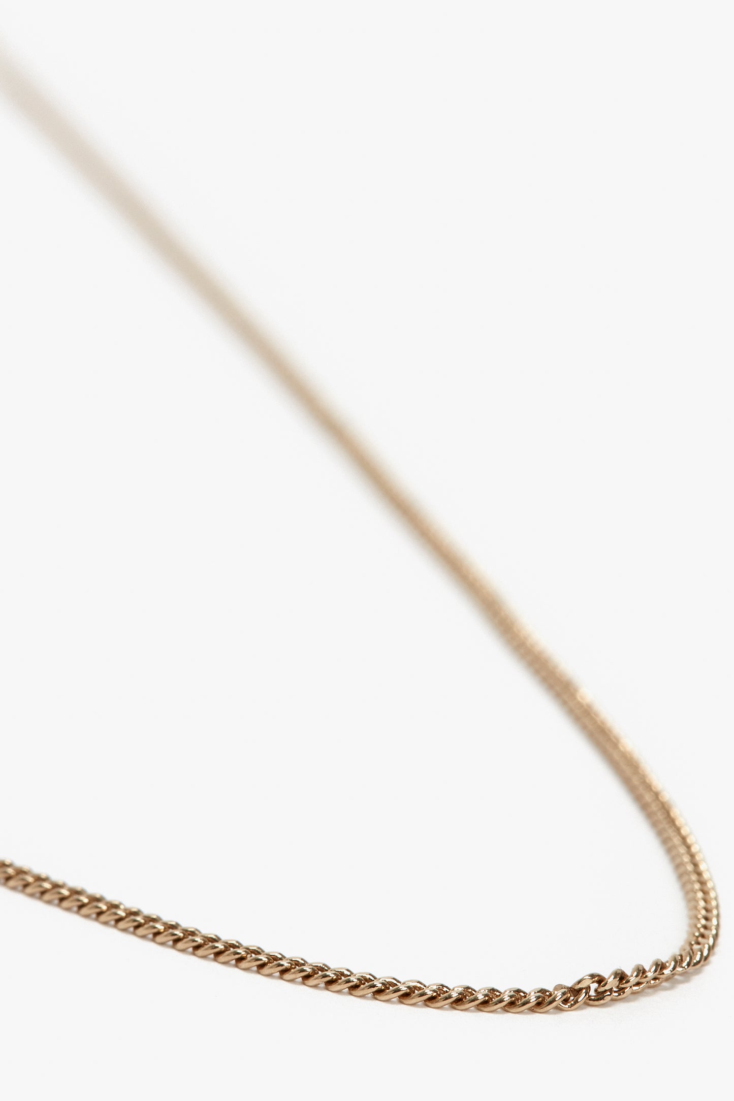 A close-up of a delicate Exclusive Long Fine Chain In Gold gold-plated brass necklace by Victoria Beckham, reminiscent of Victoria Beckham's timeless elegance, against a white background.