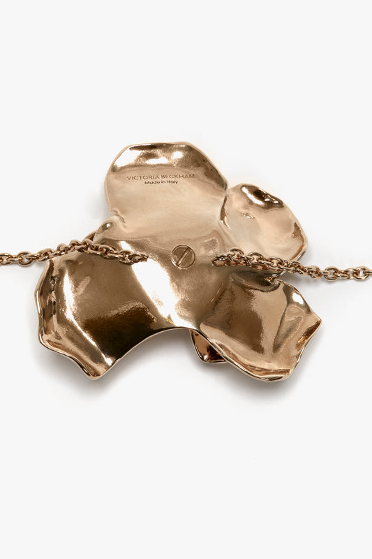 Exclusive Flower Bracelet in Gold by Victoria Beckham, in an abstract, irregular shape with a gold brushed brass finish and the engraved text "victoria beckham" on a thin, adjustable chain.