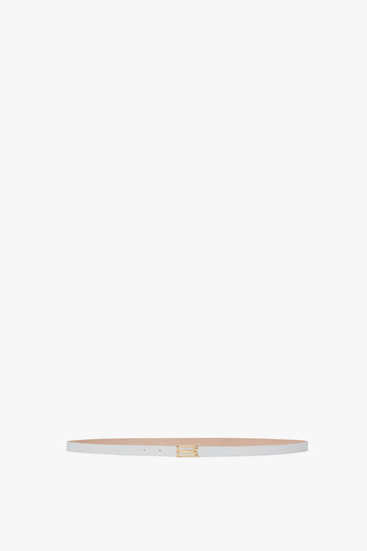 A slim beige Exclusive Micro Frame Belt crafted from smooth calf leather, with a small golden buckle, displayed against a plain white background by Victoria Beckham.