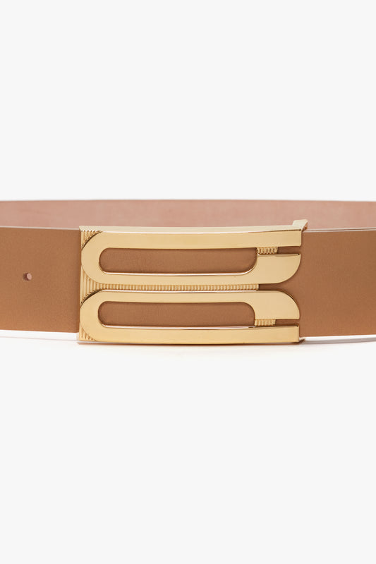 A close-up photo of a Jumbo Frame Belt in Camel Leather by Victoria Beckham, with a unique gold-toned buckle, displayed against a white background.