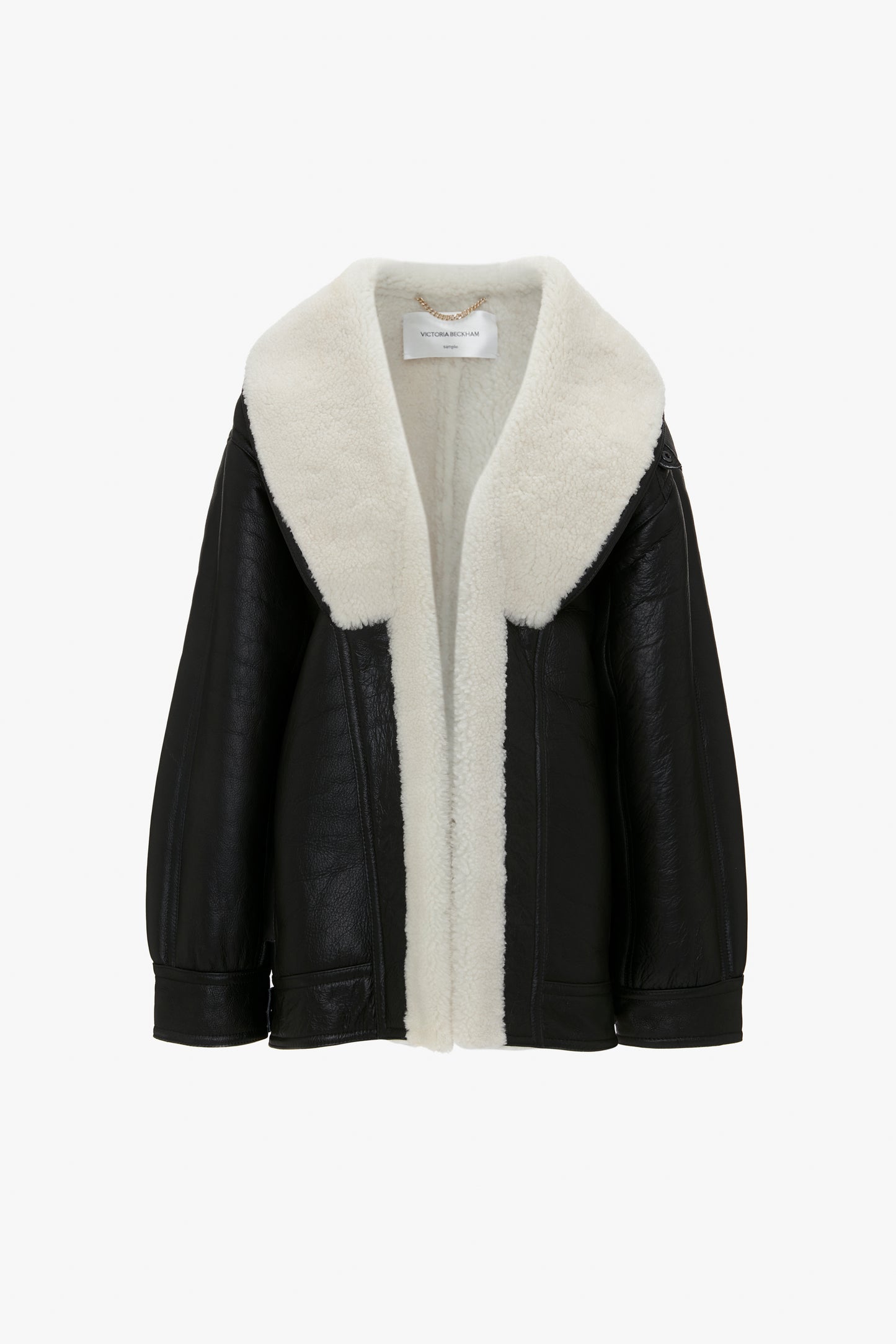 A Shearling Coat In Monochrome by Victoria Beckham, displayed against a white background, perfectly complements a cream black polo neck jumper.