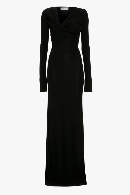 A Victoria Beckham black long-sleeved tie detail floor-length evening dress with a wrap-style top and an asymmetric cut-out at the deep v-neckline on a plain white background.