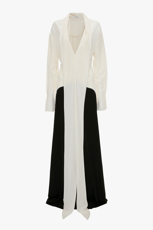 A Victoria Beckham white and black paneled evening gown with a flowing white cape on a white background.