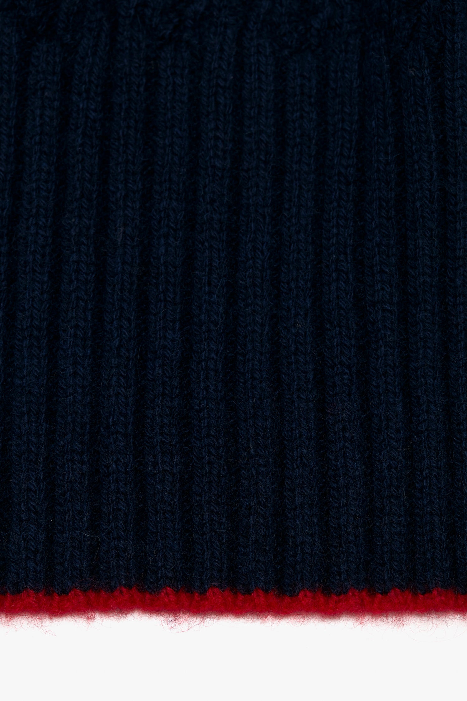 Close-up of a Victoria Beckham Exclusive Logo Patch Scarf In Navy with a thin horizontal red stripe at the bottom edge.