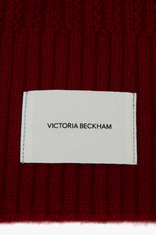 Label with "Exclusive Logo Patch Scarf In Burgundy" text on a textured red sweater by Victoria Beckham.