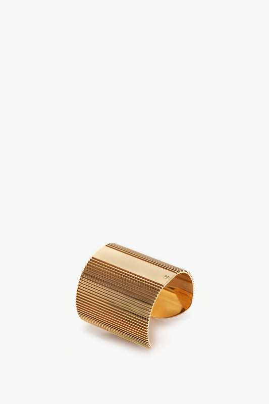 Exclusive Perfume Cuff In Gold cuff bracelet with vertical ridges displayed isolated on a white background by Victoria Beckham.