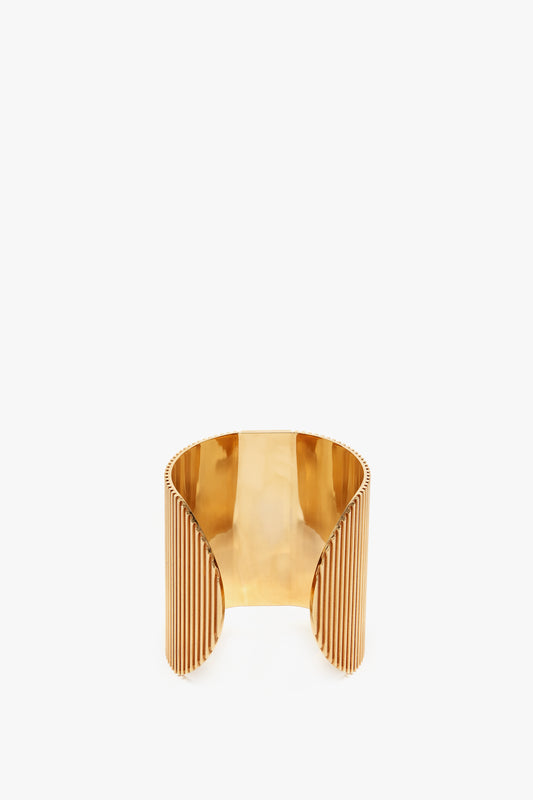 Exclusive Perfume Cuff In Gold cuff bracelet with a glossy finish and ribbed detailing on the edges, displayed against a white background by Victoria Beckham.