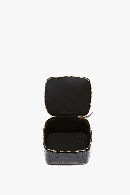 An open, empty black square Victoria Beckham leather case with a gold zipper on a white background.