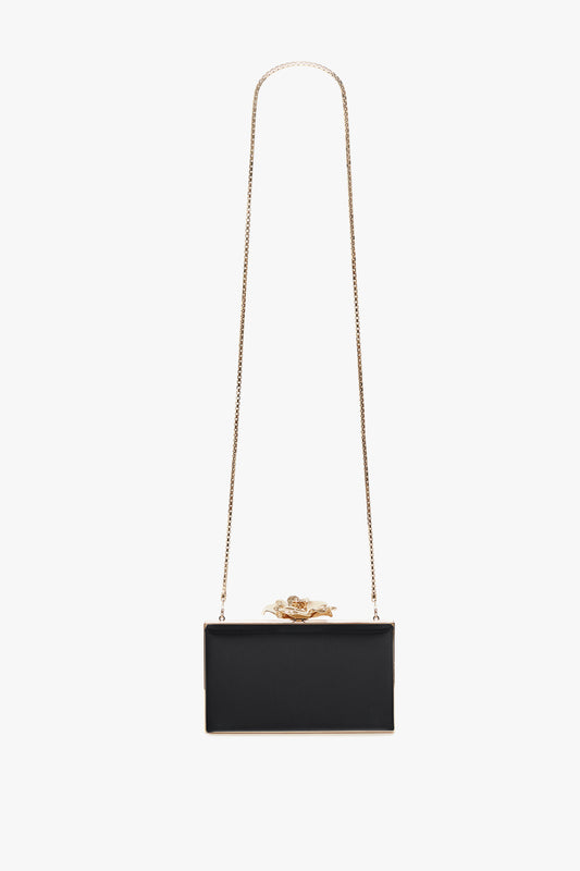 Elegant Victoria Beckham black Frame Flower Minaudiere clutch with a golden chain strap and a distinctive gold frog clasp, featuring a satin body, on a white background.