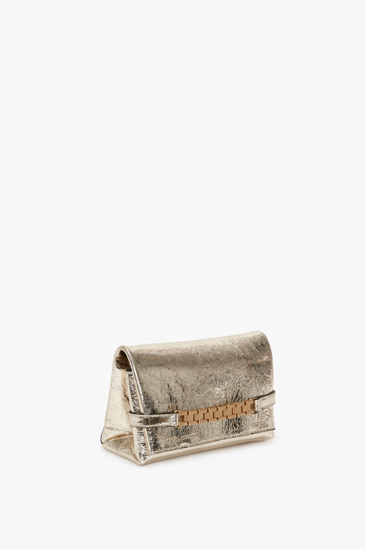Victoria Beckham Mini Chain Pouch With Long Strap In Gold Leather, with a textured finish and a horizontal strap closure, isolated on a white background.