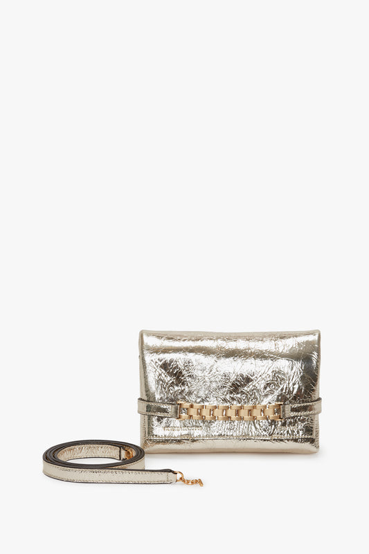 Mini Victoria Beckham metallic silver clutch purse with a crumpled texture, featuring a front flap, gold-tone hardware, and detachable chain shoulder strap, displayed against a white background.