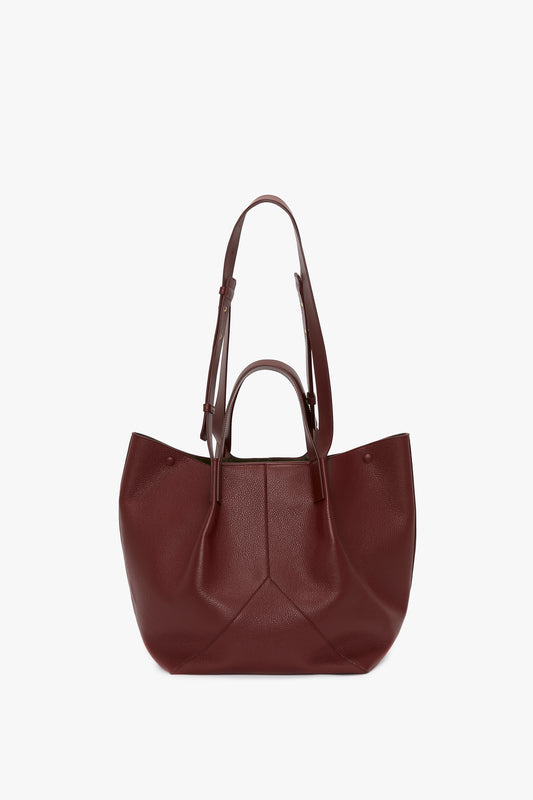 A Victoria Beckham burgundy grained leather tote bag with a geometric pattern and two handles, displayed against a white background.