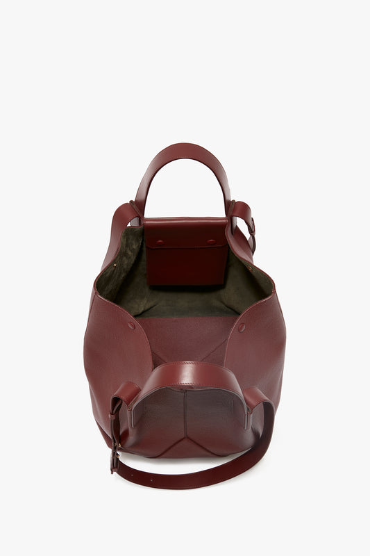 Open-top Victoria Beckham Burgundy grained leather medium tote with a structured handle and adjustable straps, viewed from above on a white background.