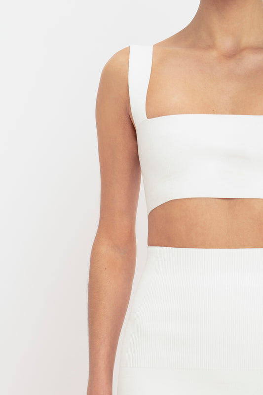 Close-up of a woman wearing a white strap bandeau top and high-waisted Victoria Beckham Body Fitted Midi Skirt, showing her upper body and arm from the side.