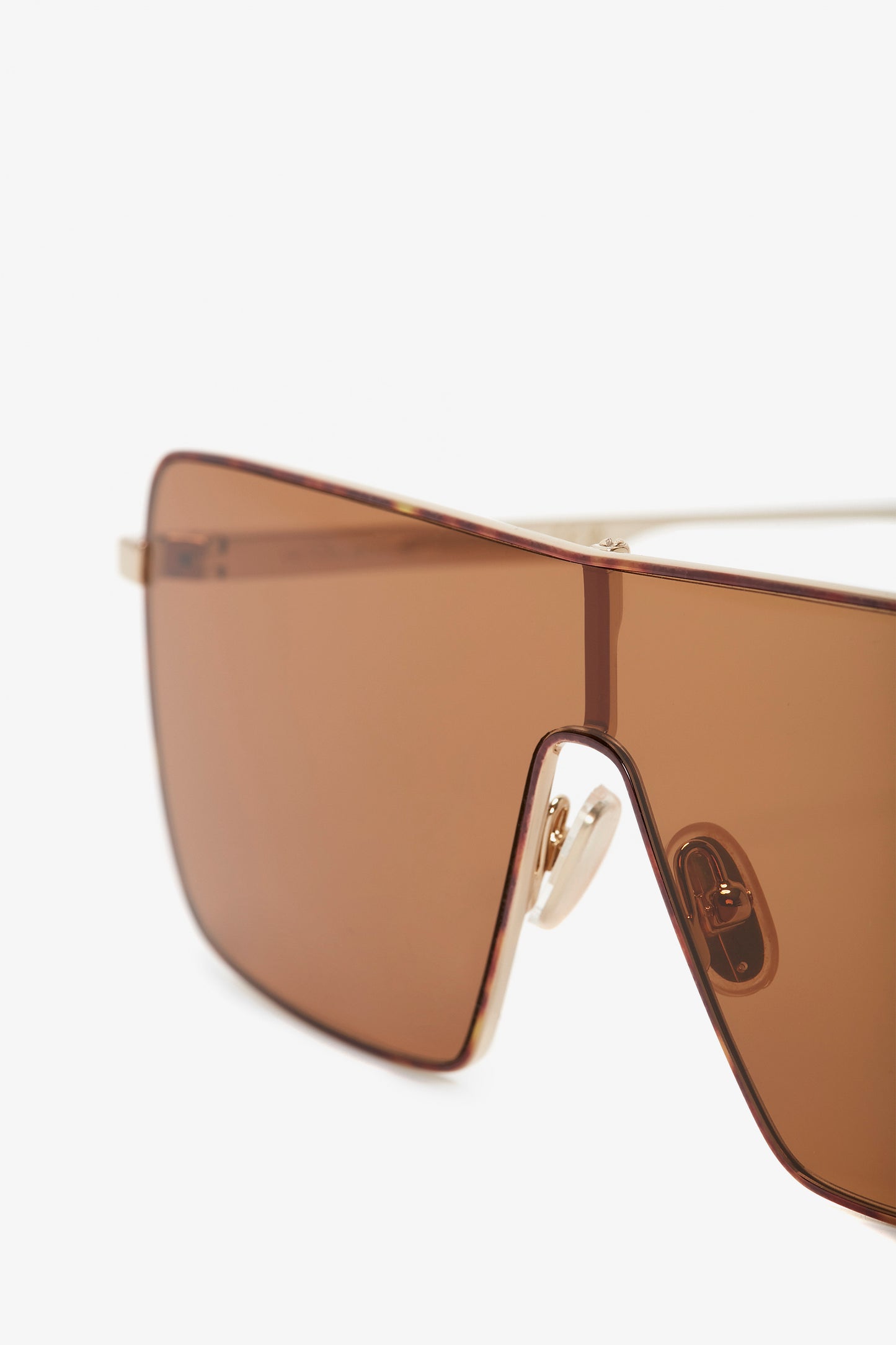 Close-up of Rectangular Visor Gold-Framed Sunglasses with caramel lenses and nose pads, featuring the Victoria Beckham logo.
