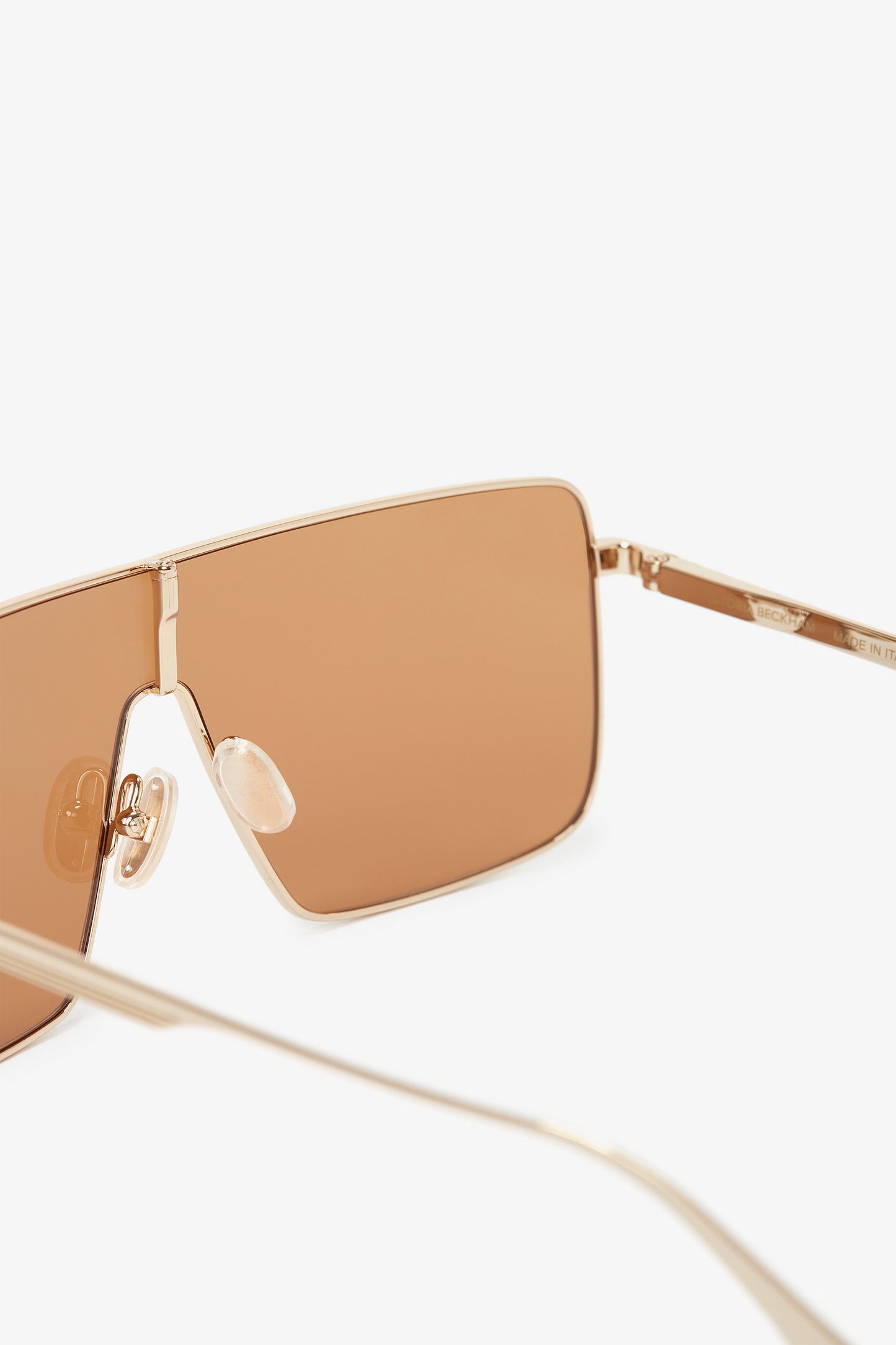 Close-up of Victoria Beckham Rectangular Visor Gold-Framed Sunglasses with caramel lenses on a white background.