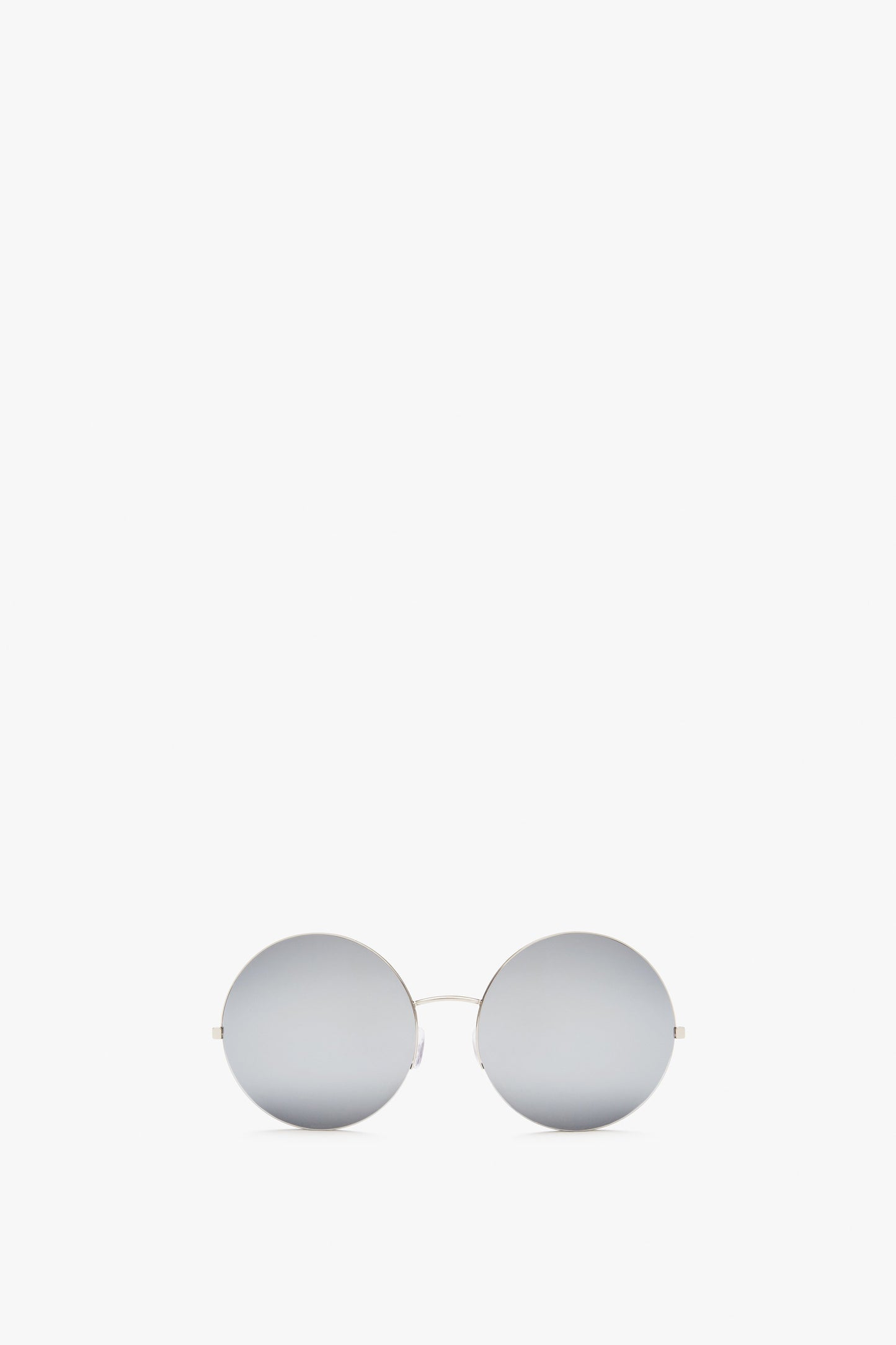 Pair of Victoria Beckham Supra Round, silver-mirrored sunglasses with thin, metallic frames and a minimalist design featuring Zeiss certified lenses for UV protection, positioned against a plain white background.