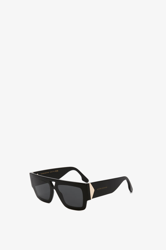Victoria Beckham V Plaque Frame Sunglasses In Black with sleek acetate frames and dark lenses, isolated on a white background.
